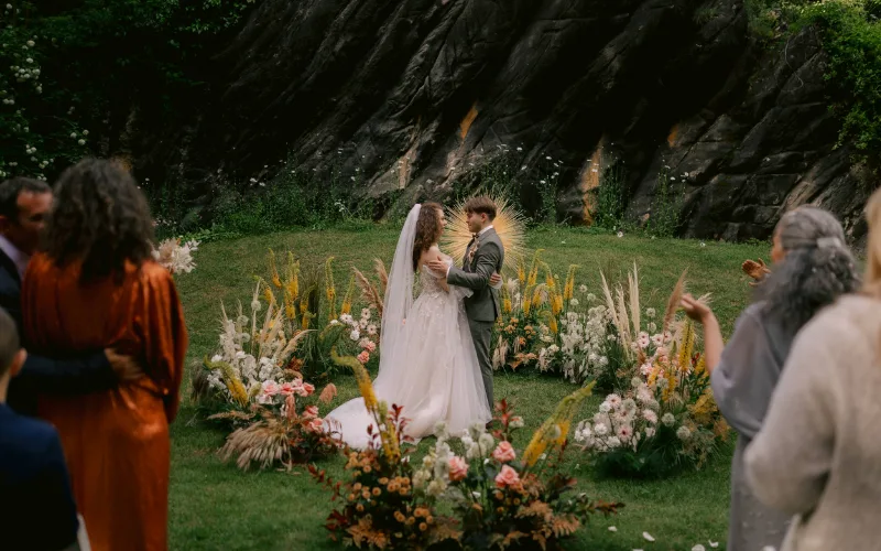 Ceremony among wildflower arrangements with guests watching