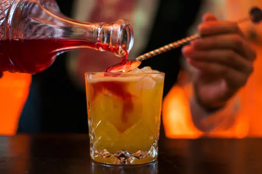 Cocktail being poured into a glass at a bar