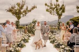 bride and groom walking down a wedding isle in spain with mountains in the background