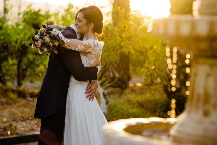 Couple embracing beside a fountain at golden hour