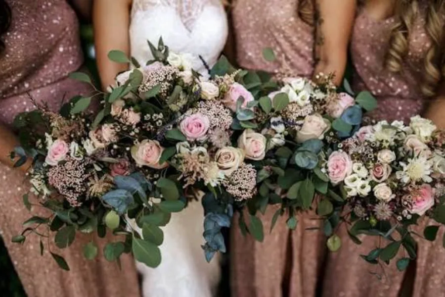 Bridesmaids holding pastel bouquets with eucalyptus