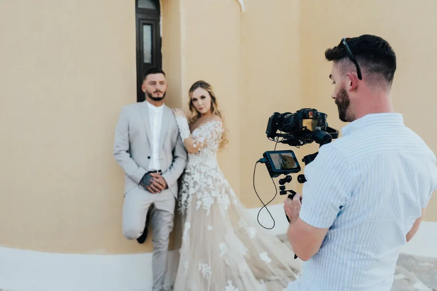 Videographer filming a bride holding a bouquet of red roses