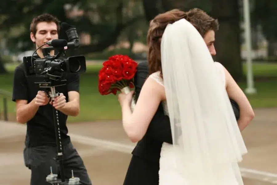 wedding videographer and a bride holding red roses