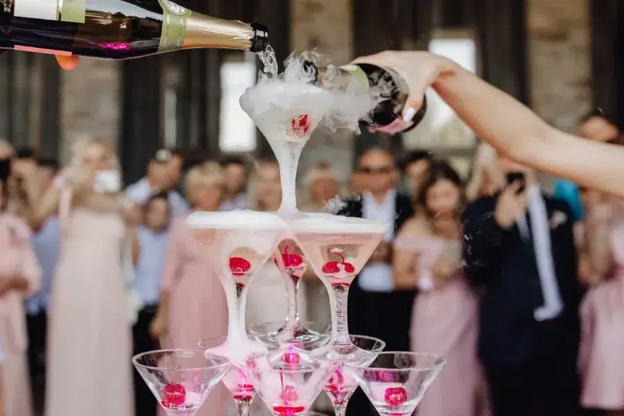 Champagne being poured into a coupe tower at a wedding